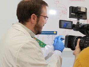 A researcher holding an item in front of a camera.
