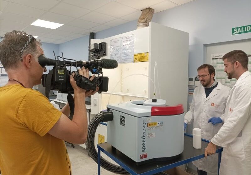 A cameraman filming two researchers in a laboratory.