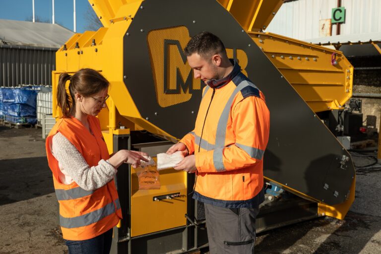 Two people talking in front of a yellow machine.