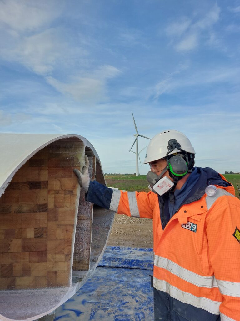 Man in safety clothing inspecting wind blade.