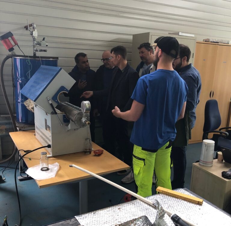 Group of men looking at lab equipment.