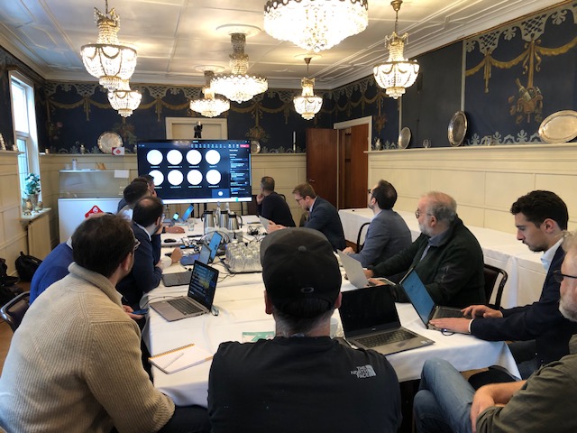 People seated around a table facing a presentation screen.
