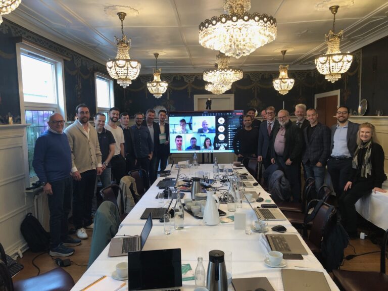Group of people standing around a table with screen in centre