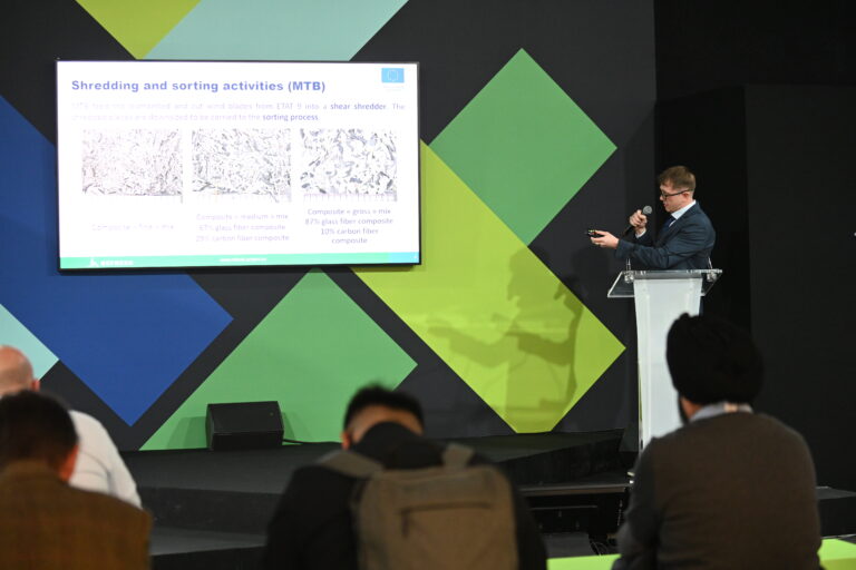 A man presenting a slide in front of a seated audience.