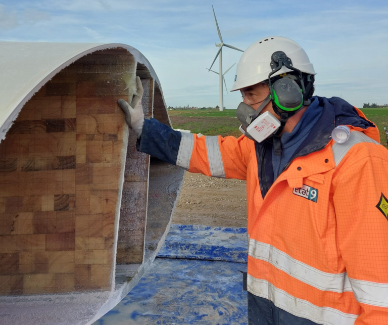 Man in PPE looking into turbine blade.