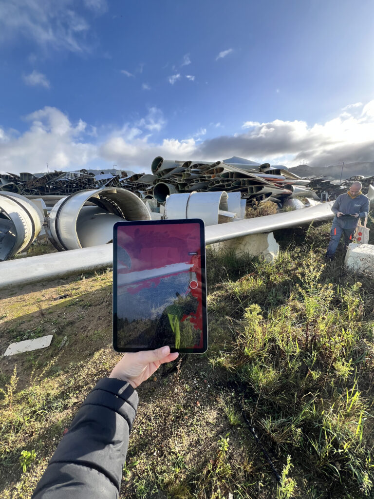 Wind turbine blades on the ground in a field.
