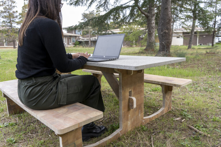 Woman sitting a picnic table outside.