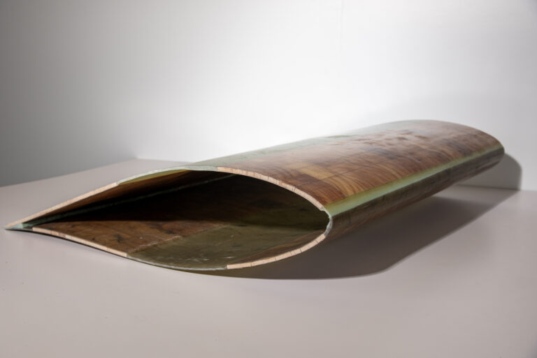 A section of a wind turbine blade, lying on the ground.