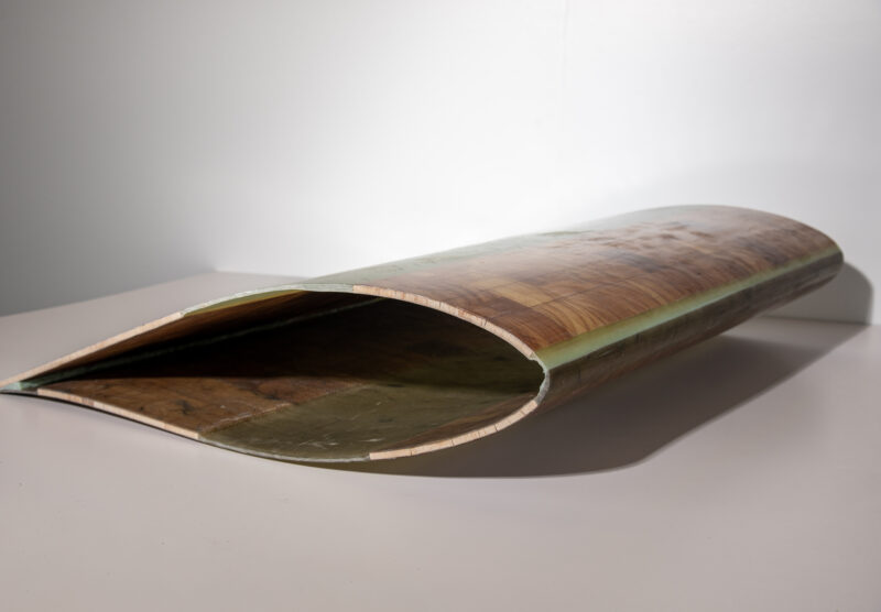 A section of a wind turbine blade, lying on the ground.