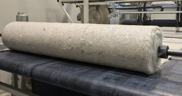 A roll of beige material lying on a black surface.