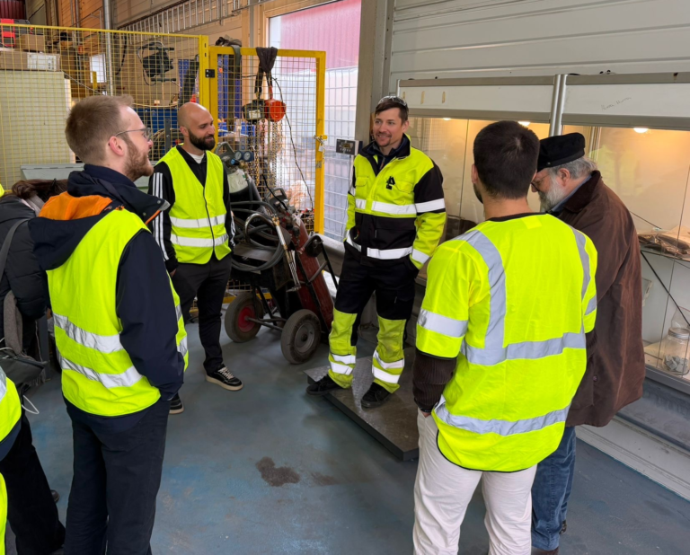Group of people in yellow jackets in a factory.