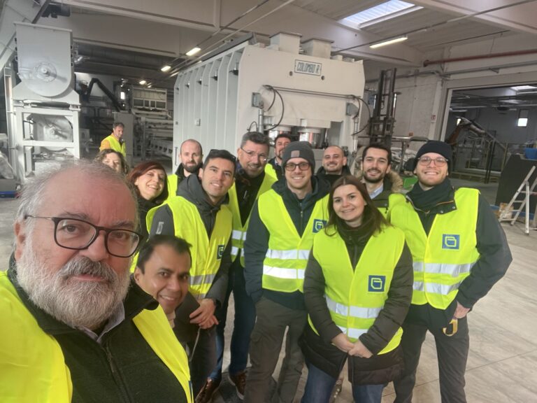 Selfie of group of people in yellow jackets in factory.